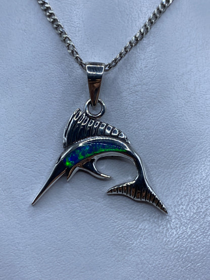 Dije de plata .950 con forma de marlin y opalo de fuego azul, colgando de cadena en el pecho