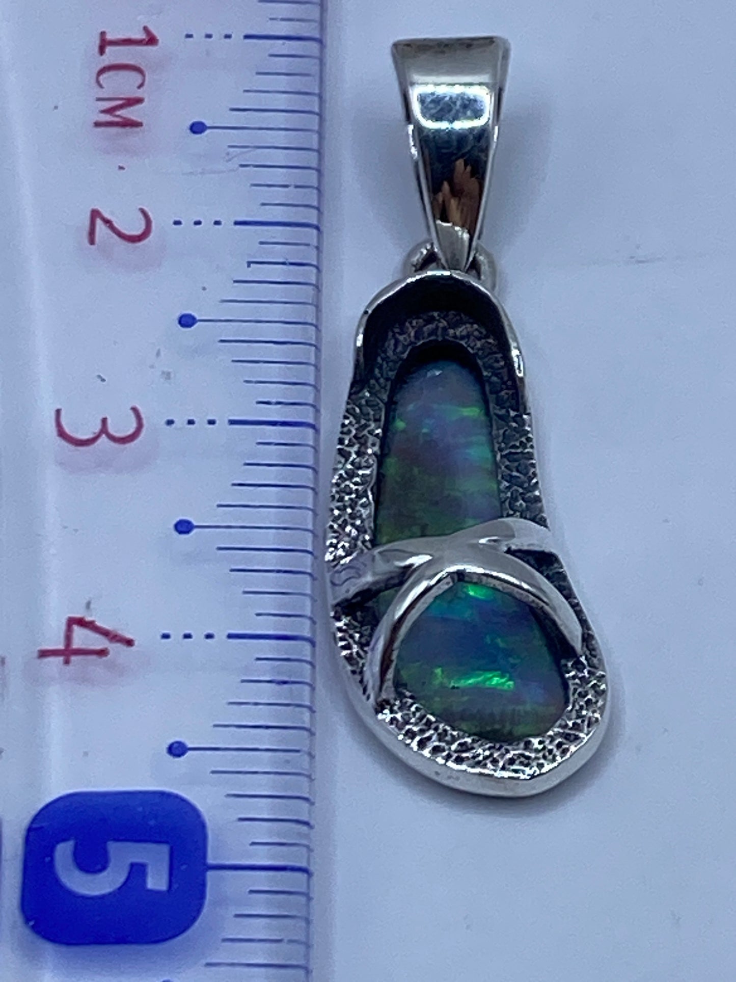 Dije sin cadena mostrando la pureza de la plata .950 y el destellar del ópalo