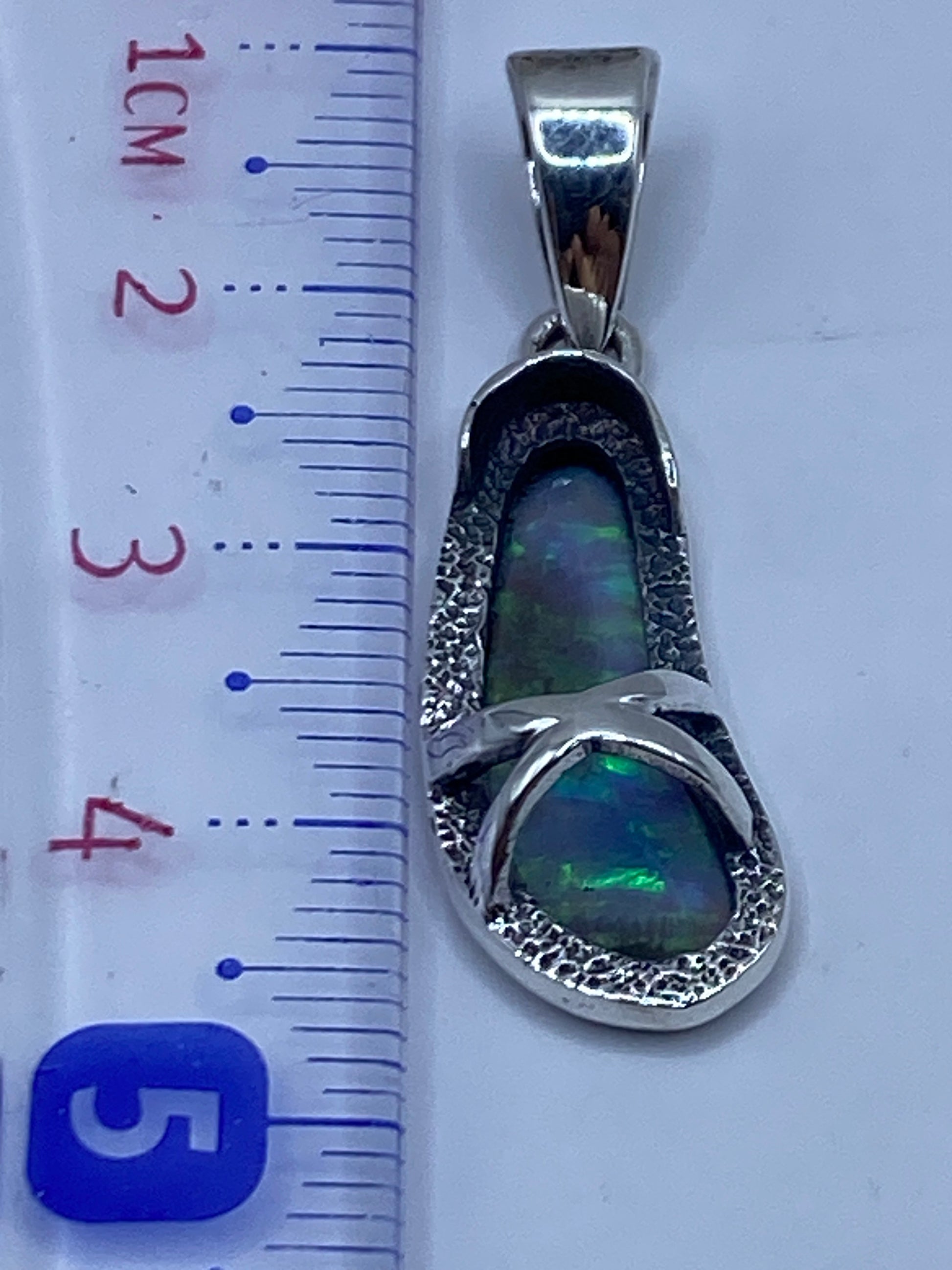 Dije sin cadena mostrando la pureza de la plata .950 y el destellar del ópalo