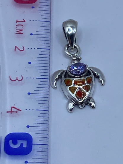 Tortuga de plata con ópalo naranja en la mano, mostrando el tamaño compacto