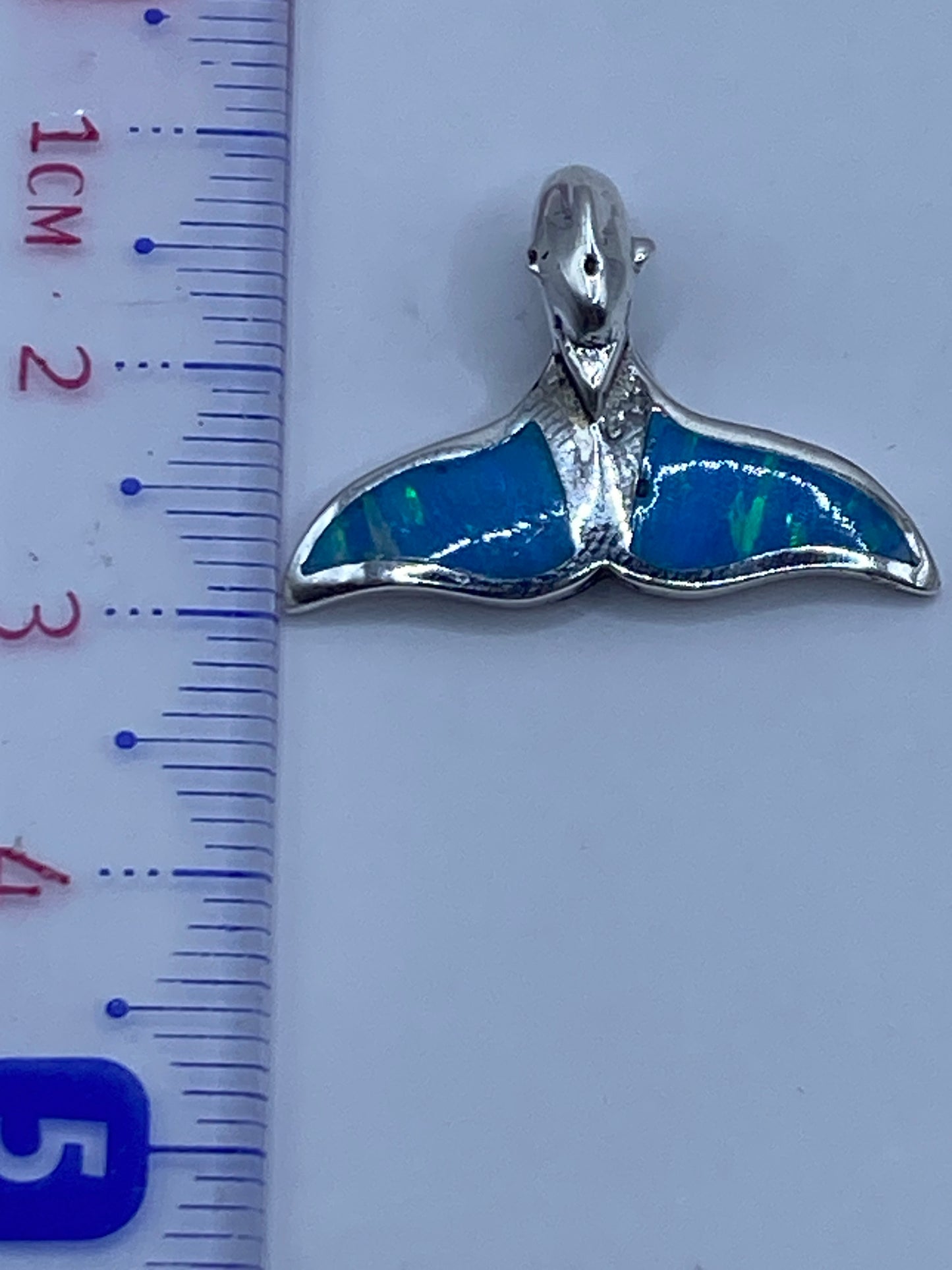 Detalle lateral del dije ballena en plata .950 con piedra de ópalo incrustada