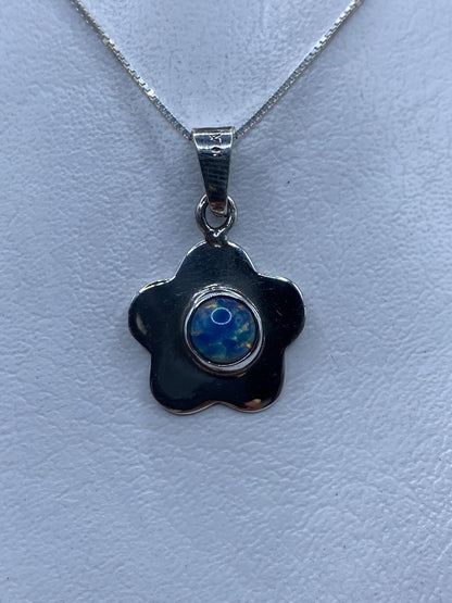 Dije floral de plata .925 con piedra multicolor azul y amarilla, colgado de una cadena plateada