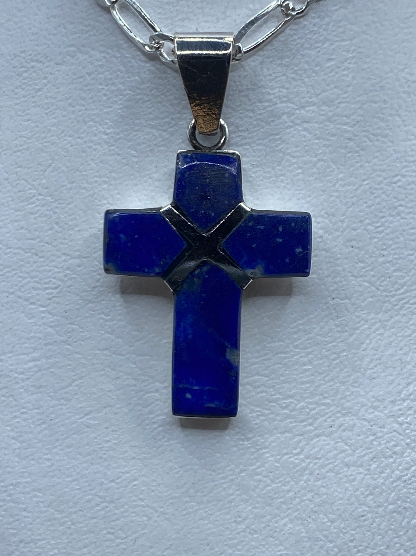 Dije cruz de plata .950 con lapislázuli azul profundo engastado, colgando de cadena plateada