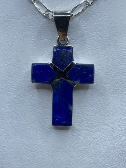 Dije cruz de plata .950 con lapislázuli azul profundo engastado, colgando de cadena plateada