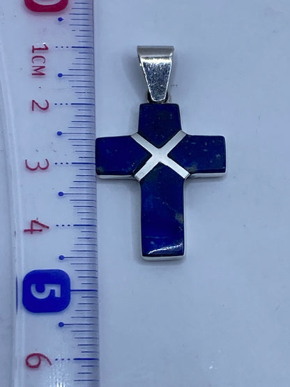 Dije cruz de plata .950 sobre superficie neutral, con hallmark .950 visible en el reverso