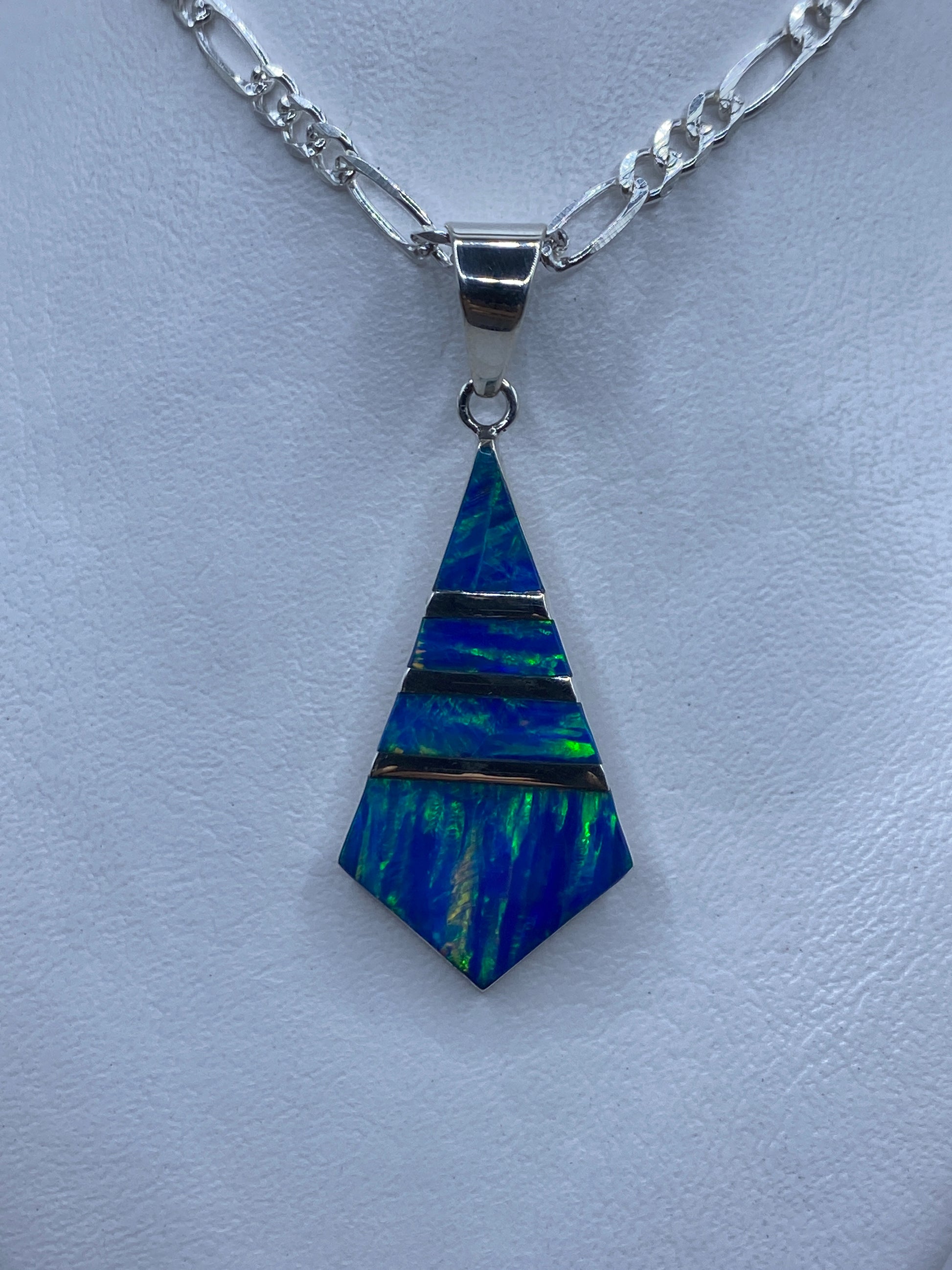 Dije de plata con ópalo de fuego azul e iridiscencias verdes, forma pentagonal, sobre cadena plateada
