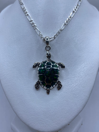 Medida del dije tortuga junto a regla, mostrando 5.2 cm de largo
