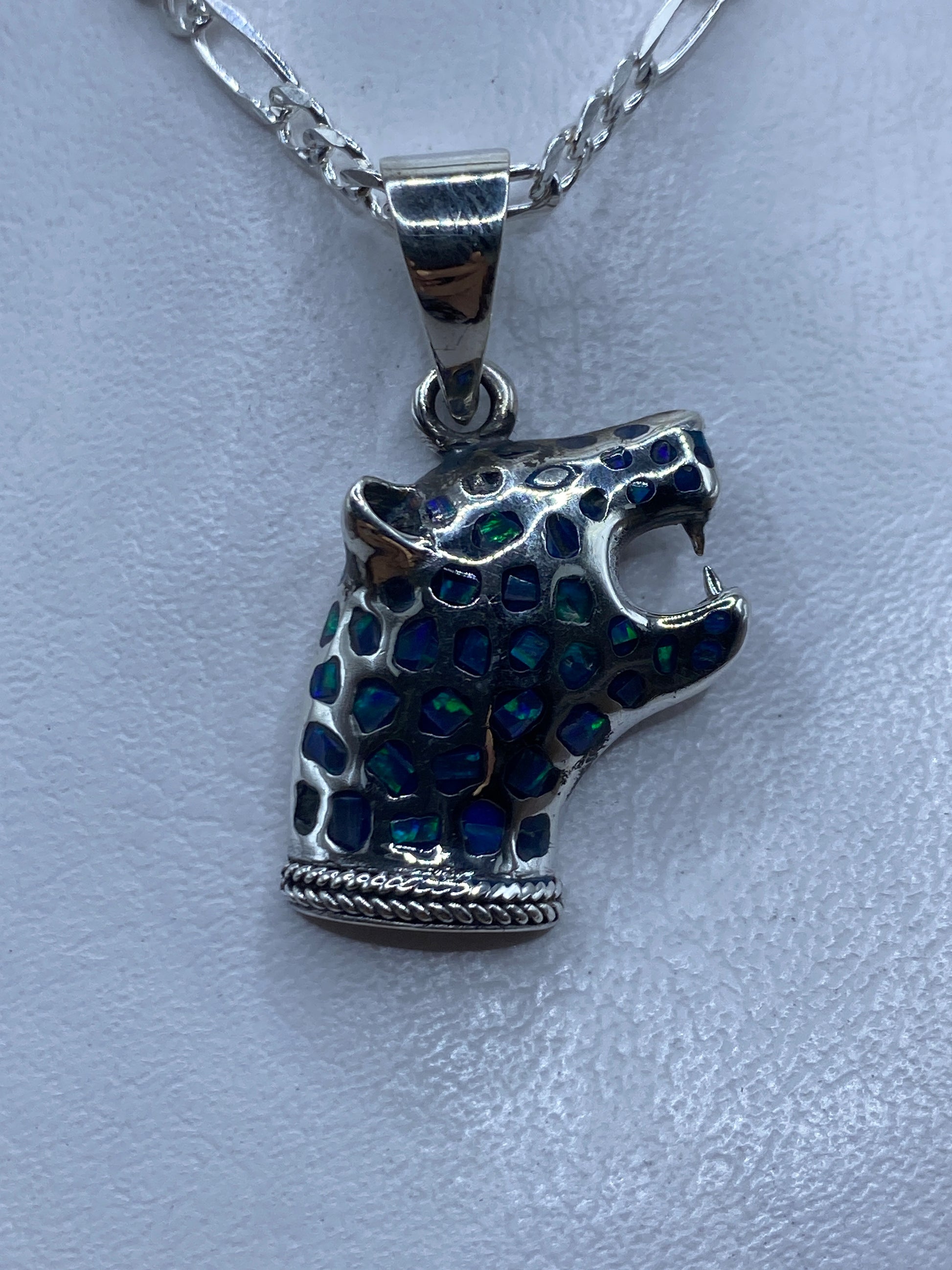 Dije de plata con ópalo de fuego azul incrustado, colgando sobre fondo claro