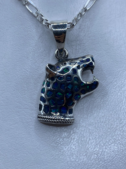 Dije de plata con ópalo de fuego azul incrustado, colgando sobre fondo claro