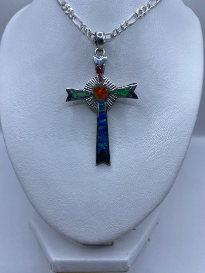 Cruz religiosa de plata con piedra ópalo que brilla en tonos rojos, verdes y azules