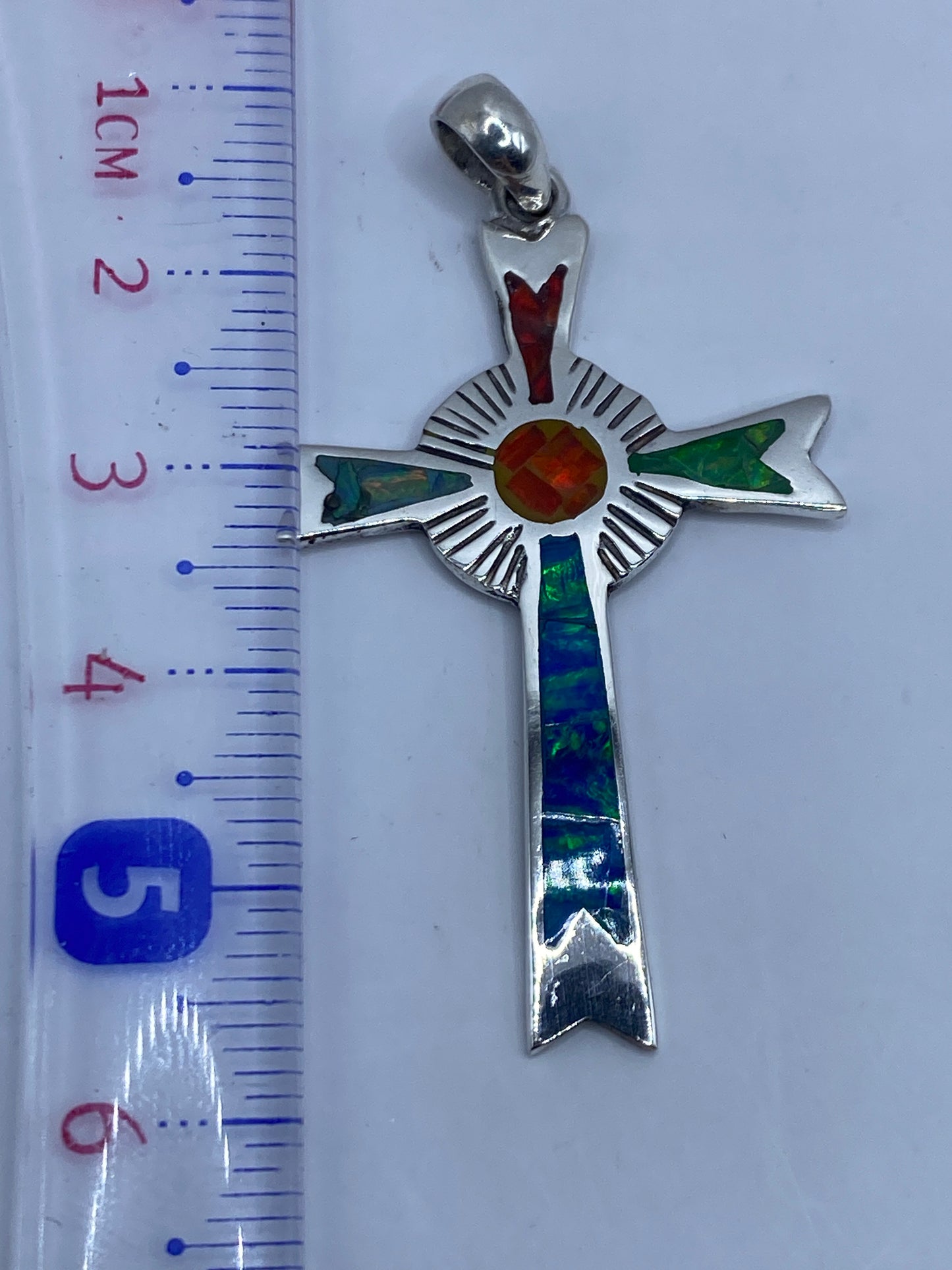 Dije cruz de plata sobre fondo blanco mostrando el Quinto .950 grabado en la parte trasera