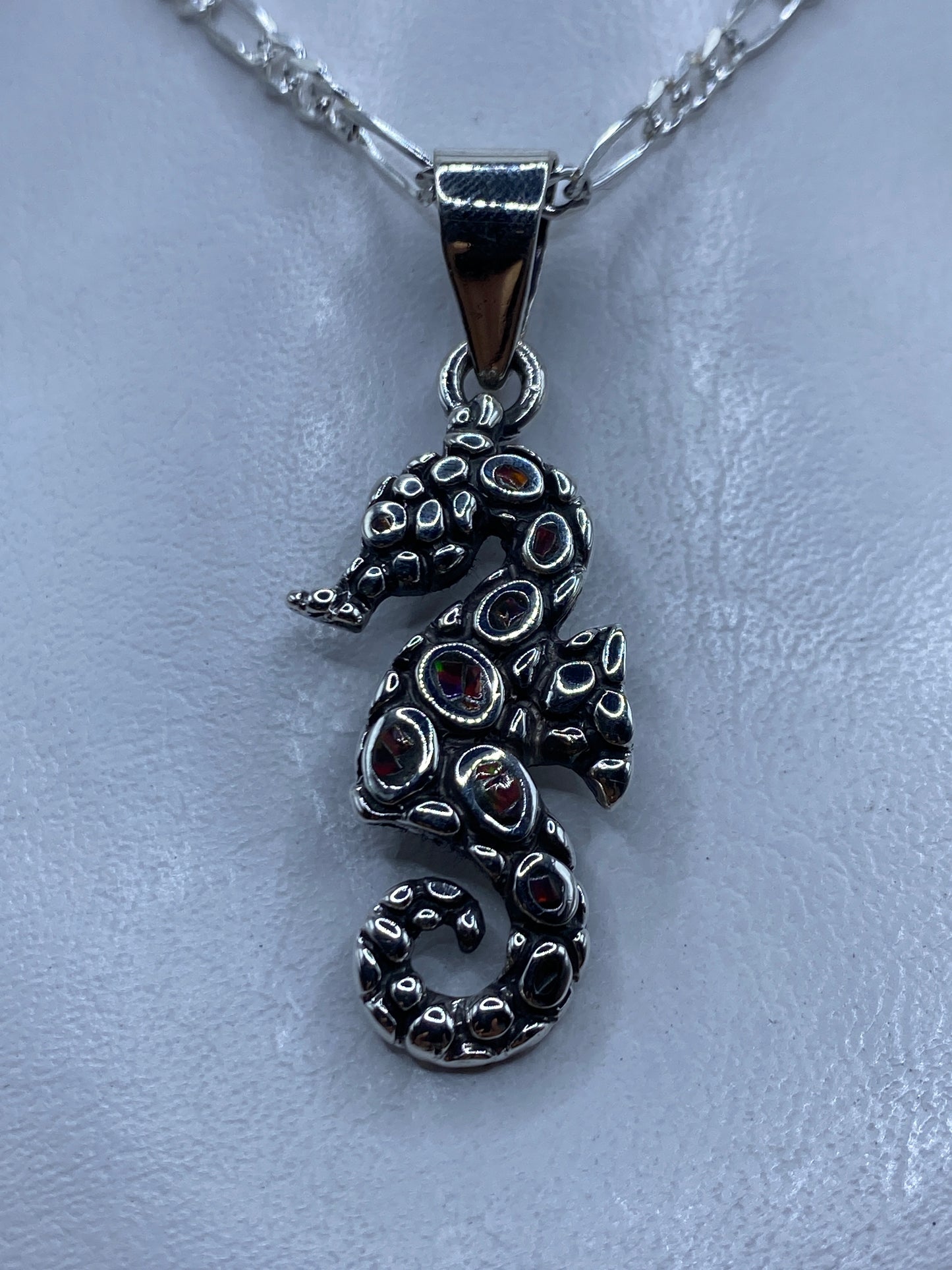 Dije caballo de mar en plata .950 con opalo de fuego multicolor engastado, colgando de cadena de plata figaro
