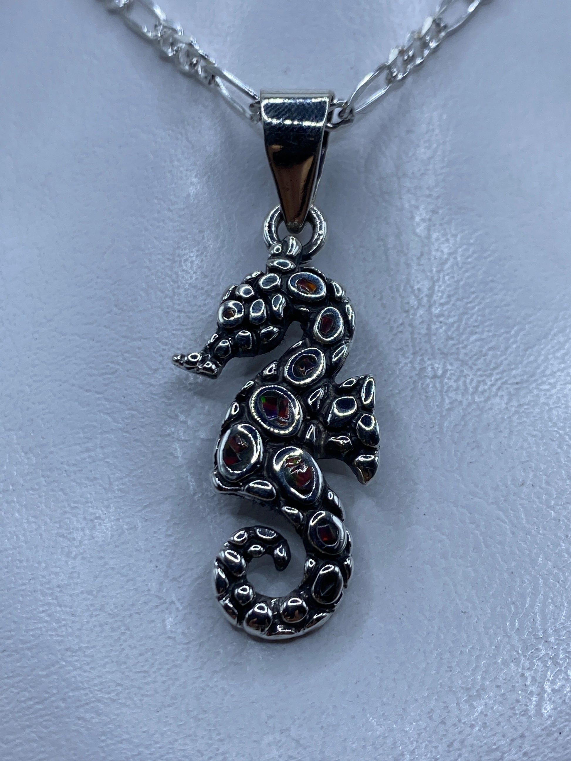 Dije caballo de mar en plata .950 con opalo de fuego multicolor engastado, colgando de cadena de plata figaro