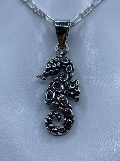 Dije caballo de mar en plata .950 con opalo de fuego multicolor engastado, colgando de cadena de plata figaro