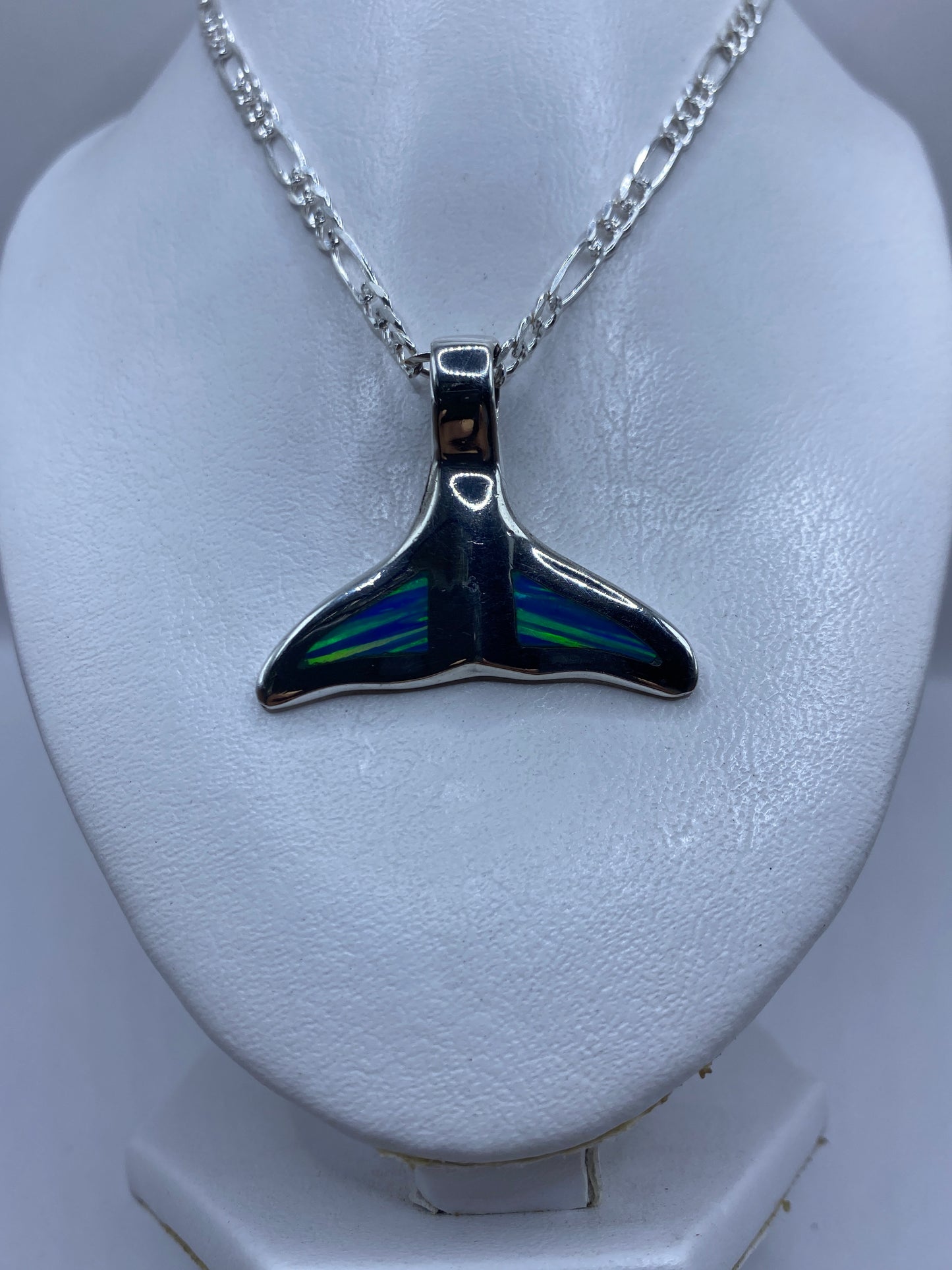 Vista frontal del dije de cola de ballena con ópalo azul brillante reflejando luz