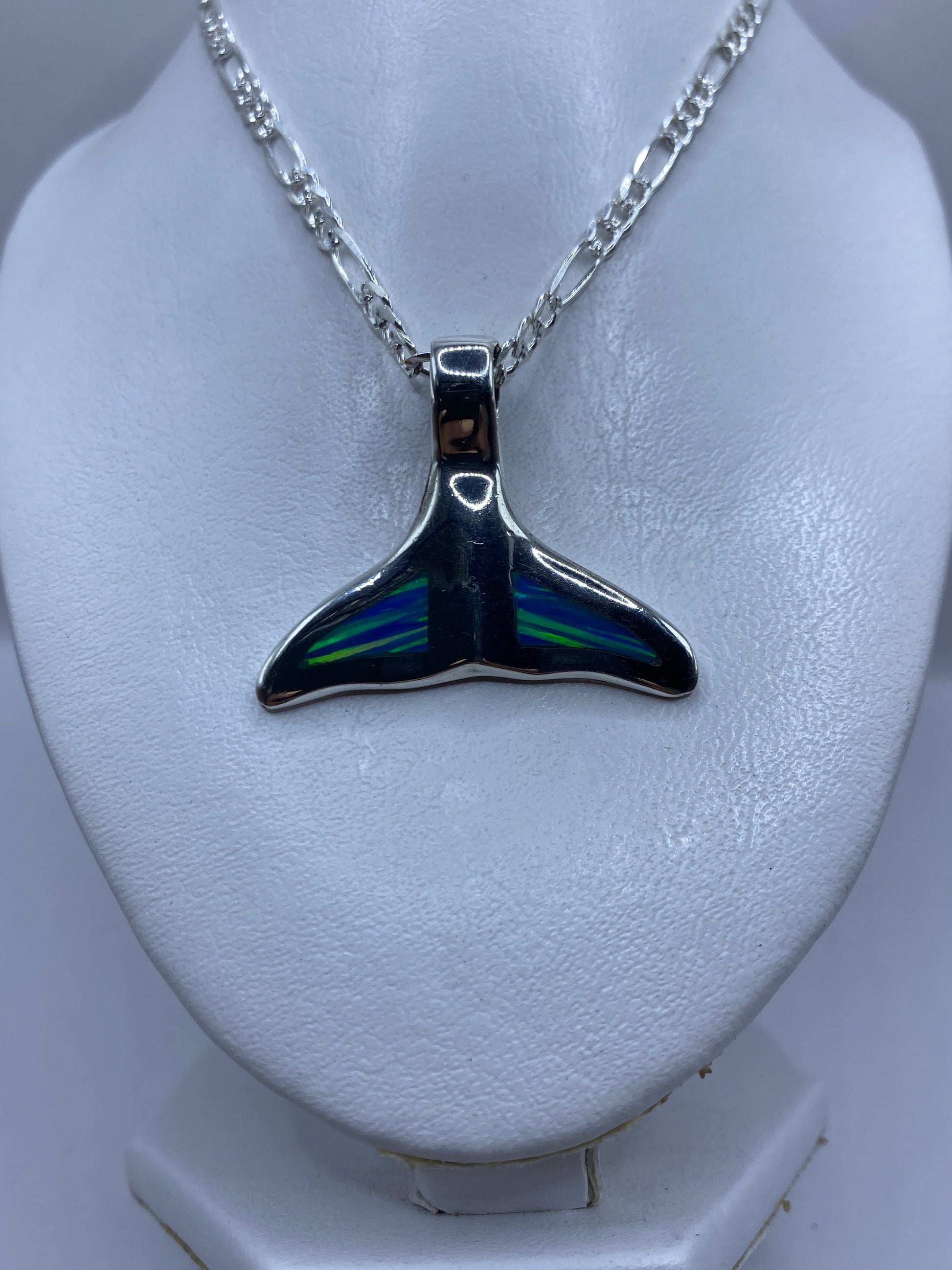 Vista frontal del dije de cola de ballena con ópalo azul brillante reflejando luz