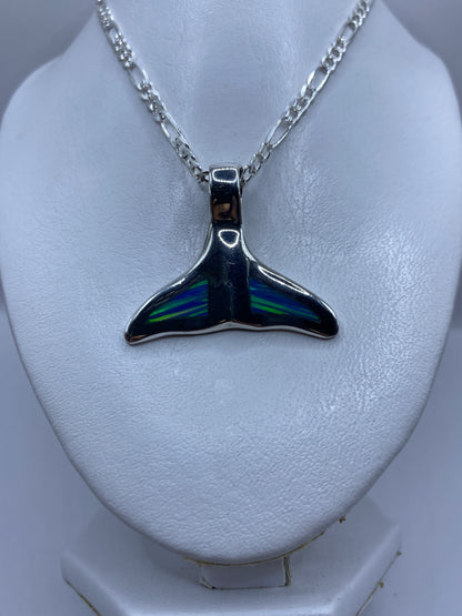 Vista frontal del dije de cola de ballena con ópalo azul brillante reflejando luz