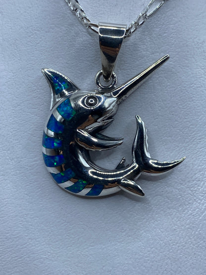 Dije marlin de plata .950 con ópalo de fuego azul, visto de frente sobre cadena