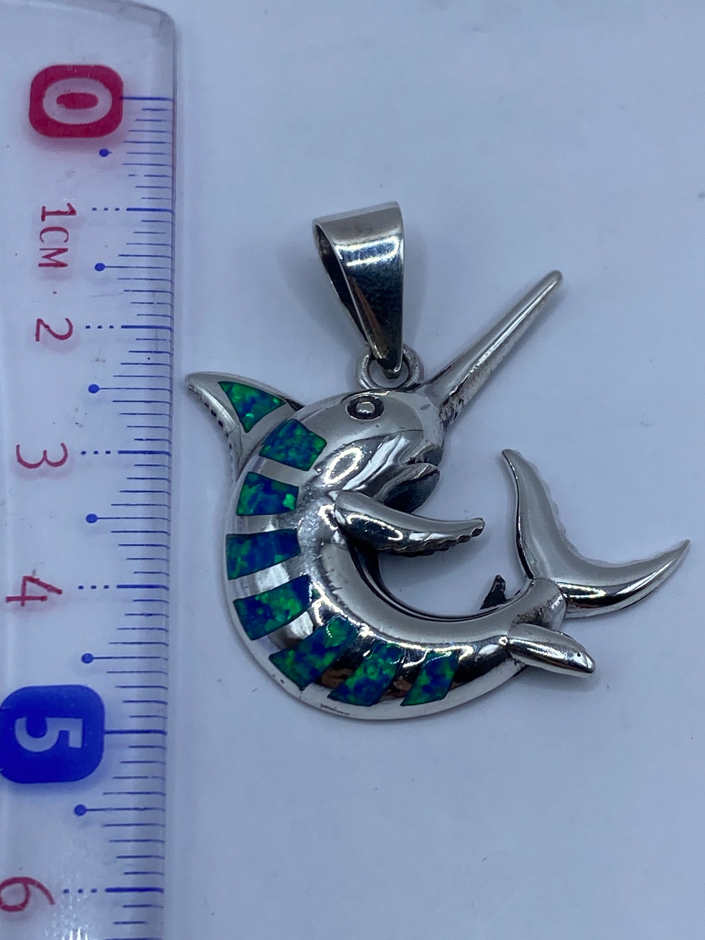 Marlin de plata .950 sobre fondo blanco con medida de escala en centímetros