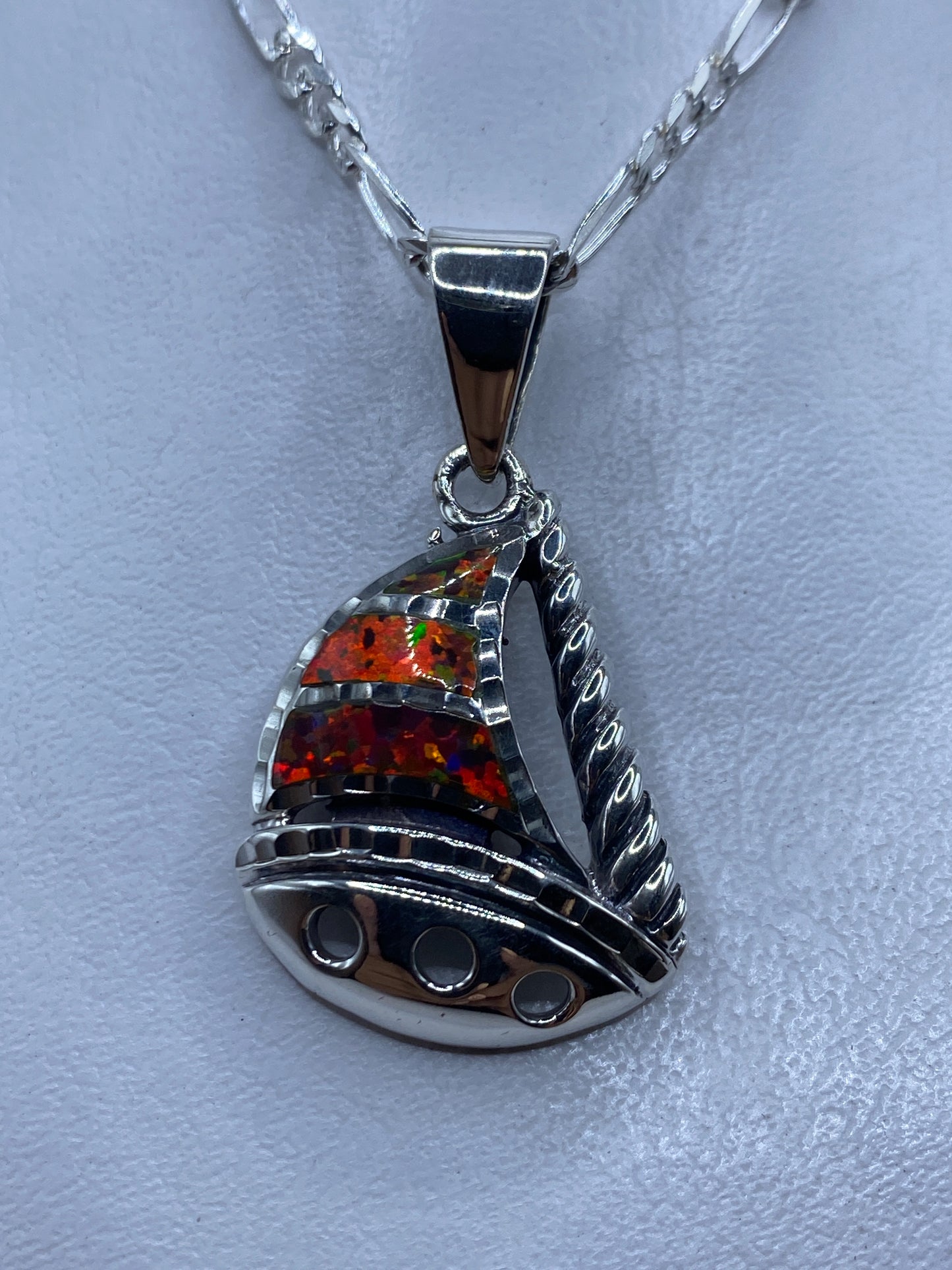 Dije de plata con ópalo de fuego multicolor en forma de vela marinera, colgando de cadena en el cuello