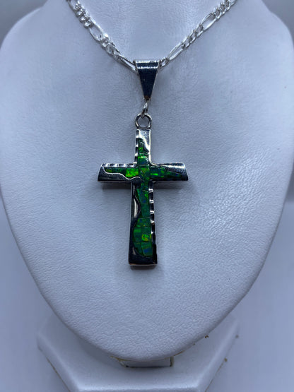 Detalle de la cruz de plata visto al cuello, mostrando el tamaño de 6 cm y el ópalo brillante
