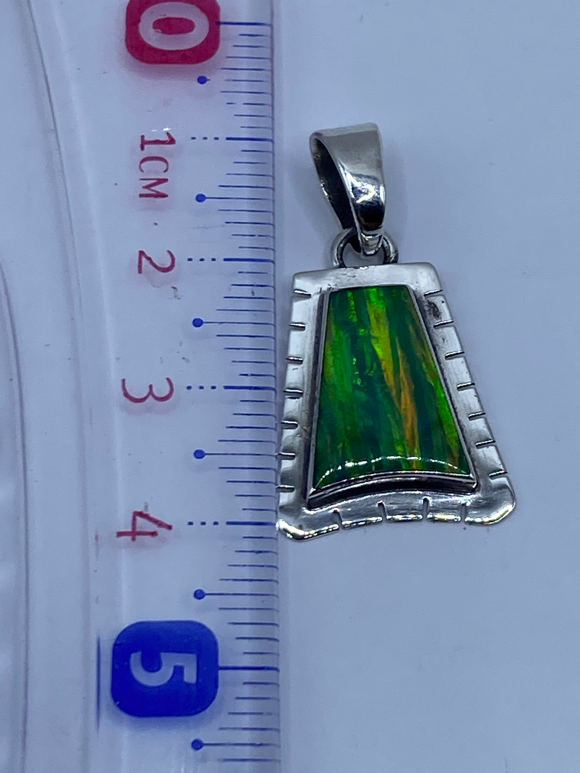 Reverso del dije con marca de platería y diseño escalonado