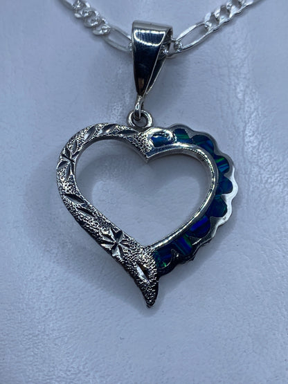 Dije de plata corazón con ópalo de fuego azul profundo, colgante sobre fondo blanco