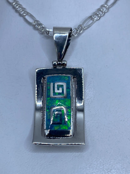 Dije de plata .950 con ópalo de fuego azul cielo y diseño geométrico prehispánico, colgando de una cadena