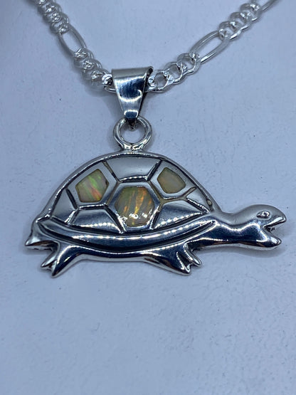 Dije de tortuga en plata .925 con ópalo de fuego multicolor colgando de cadena de plata