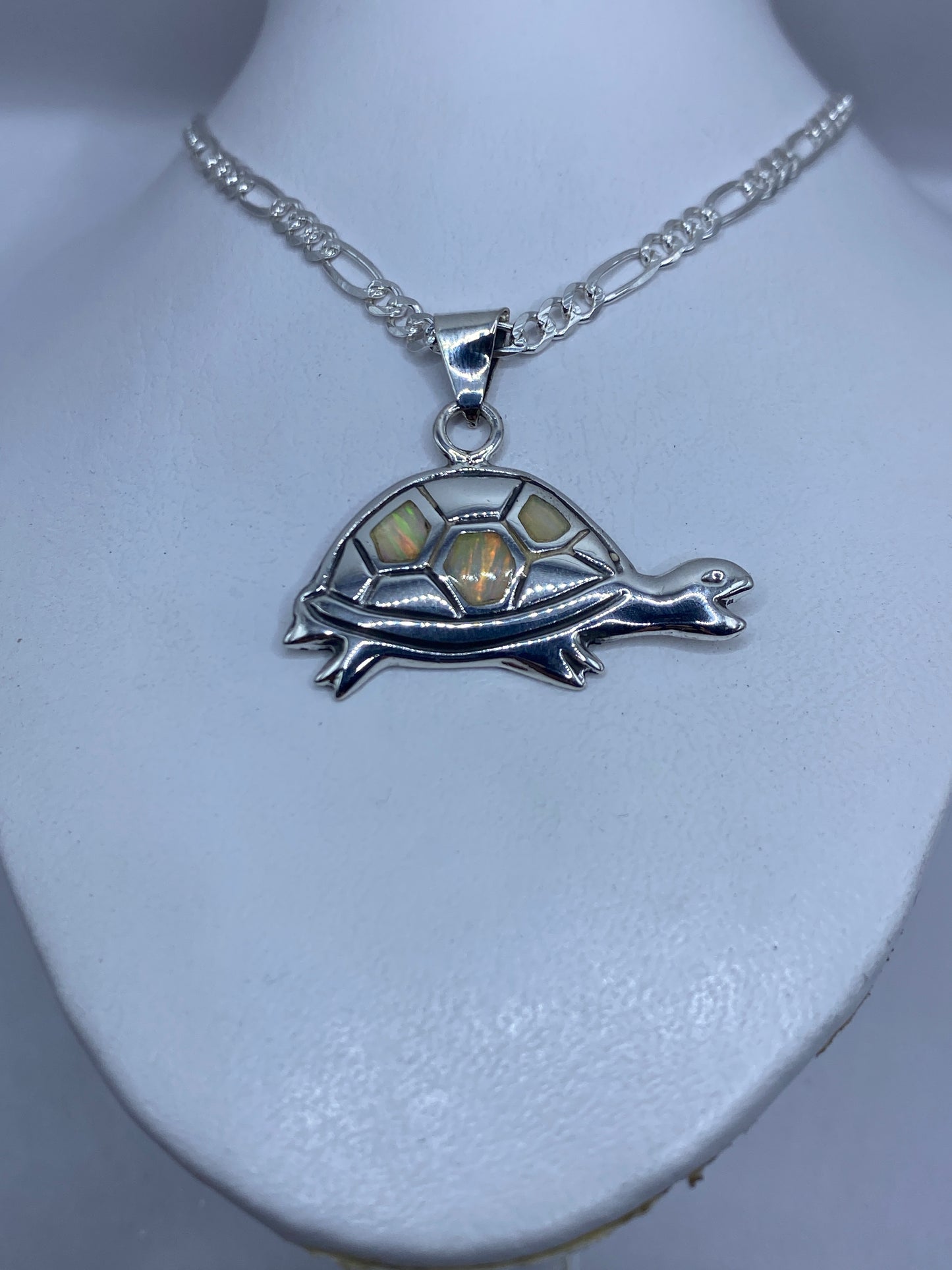 Detalle del ópalo de fuego con reflejos verdes, naranjas y dorados en la tortuga de plata