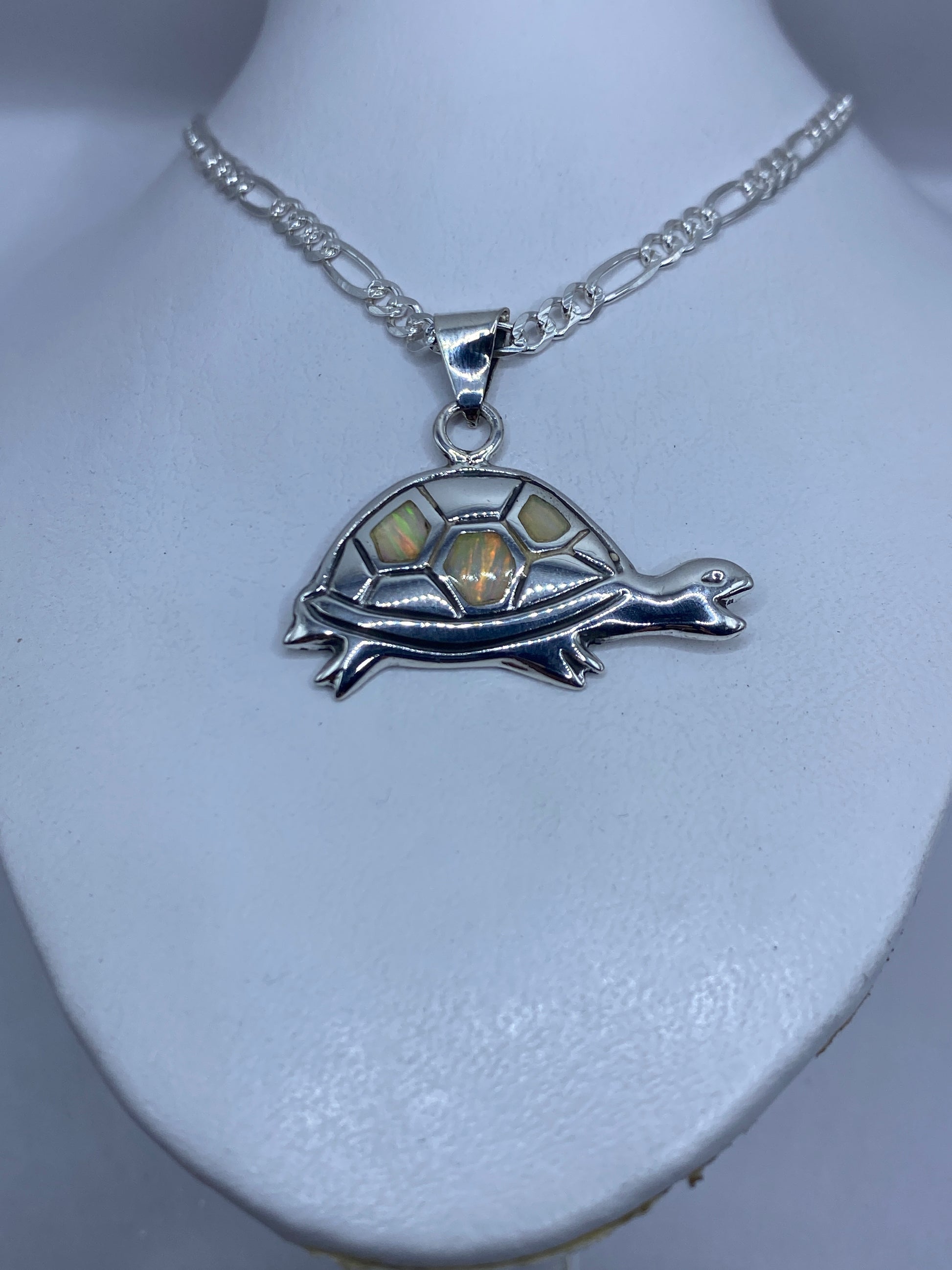 Detalle del ópalo de fuego con reflejos verdes, naranjas y dorados en la tortuga de plata