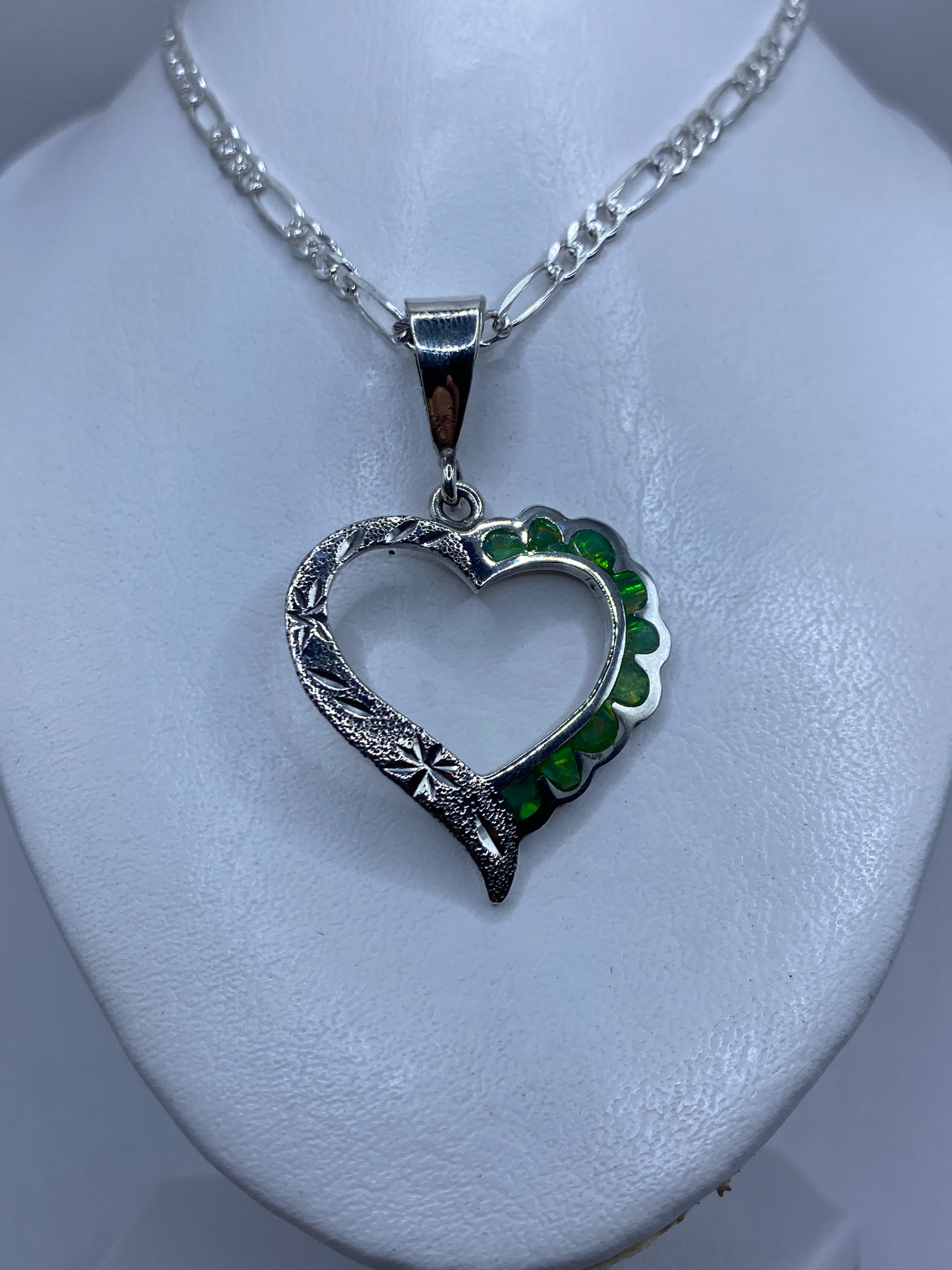 Detalle de la incrustación de ópalo de fuego con tonalidad verde luminosa en el dije corazón