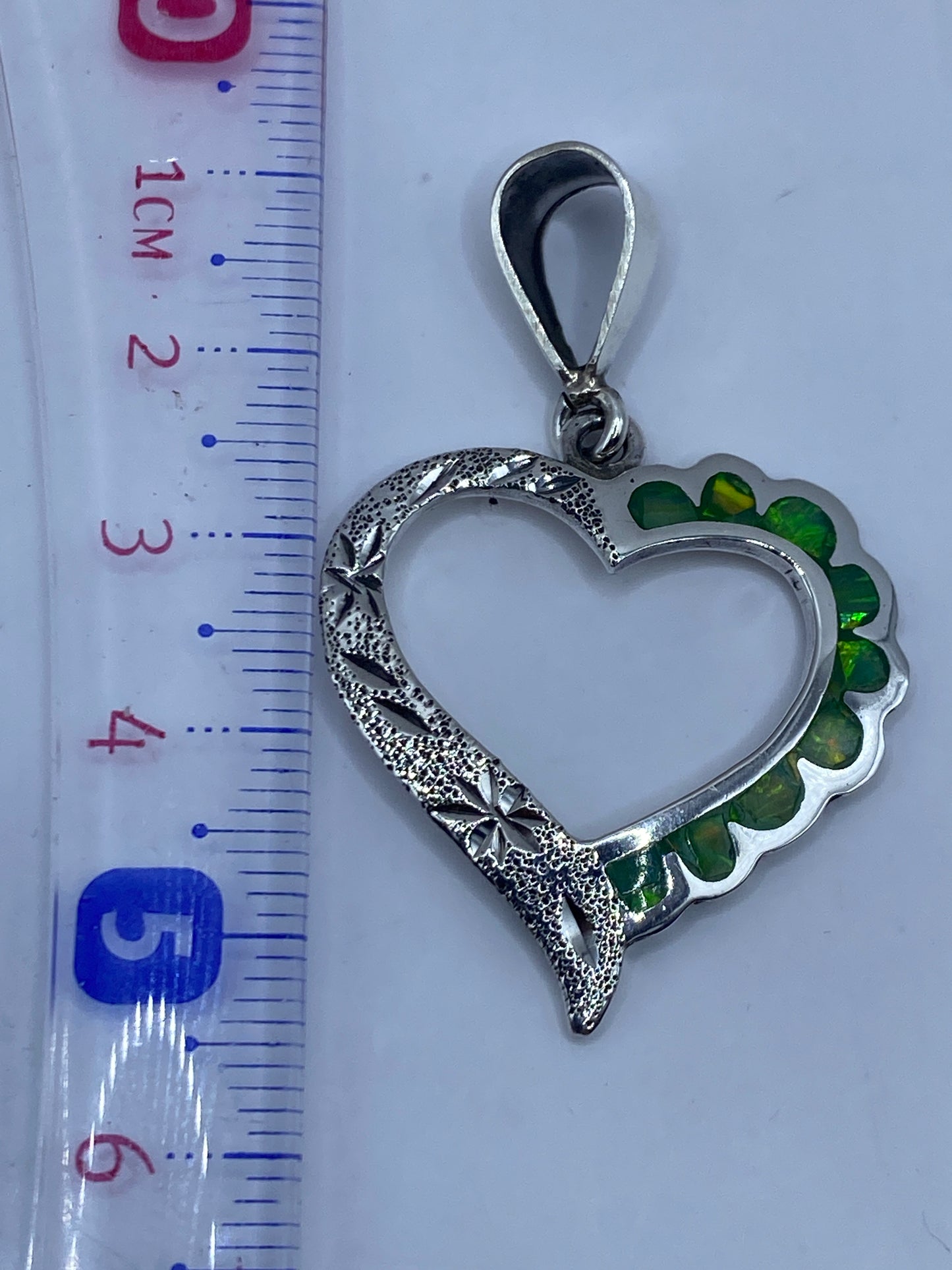 Dije corazón de 5.5 cm junto a regla mostrando el tamaño real comparado con centímetros
