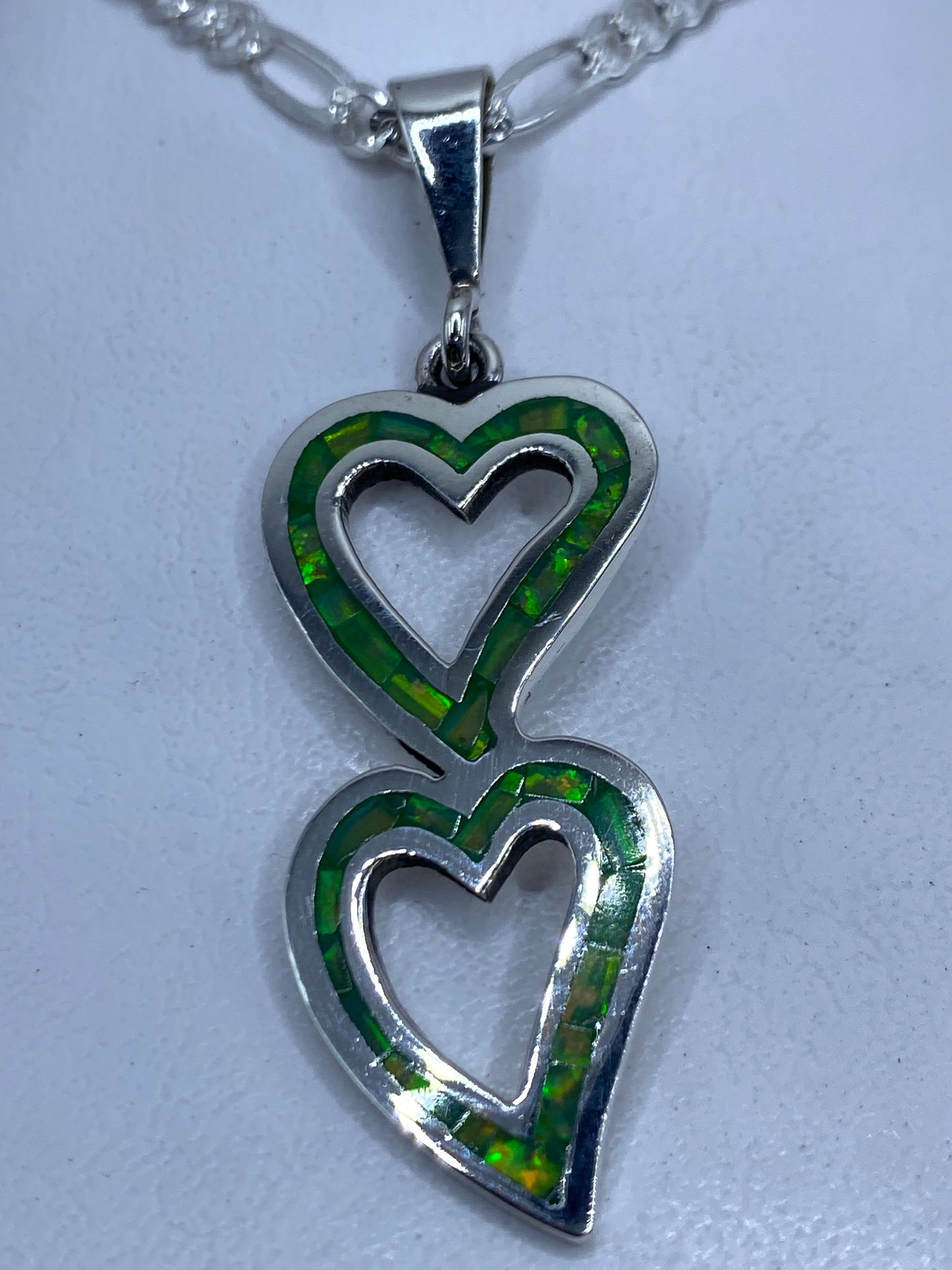 Dije de plata .950 con dos corazones apilados y Opalo de Fuego verde limón engastado