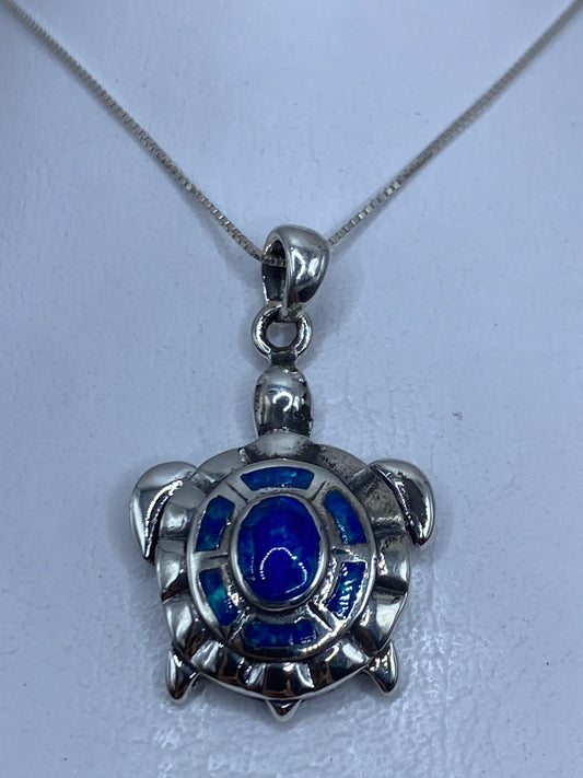 Dije tortuga de plata .950 con ópalo de fuego azul colgado en cadena plateada