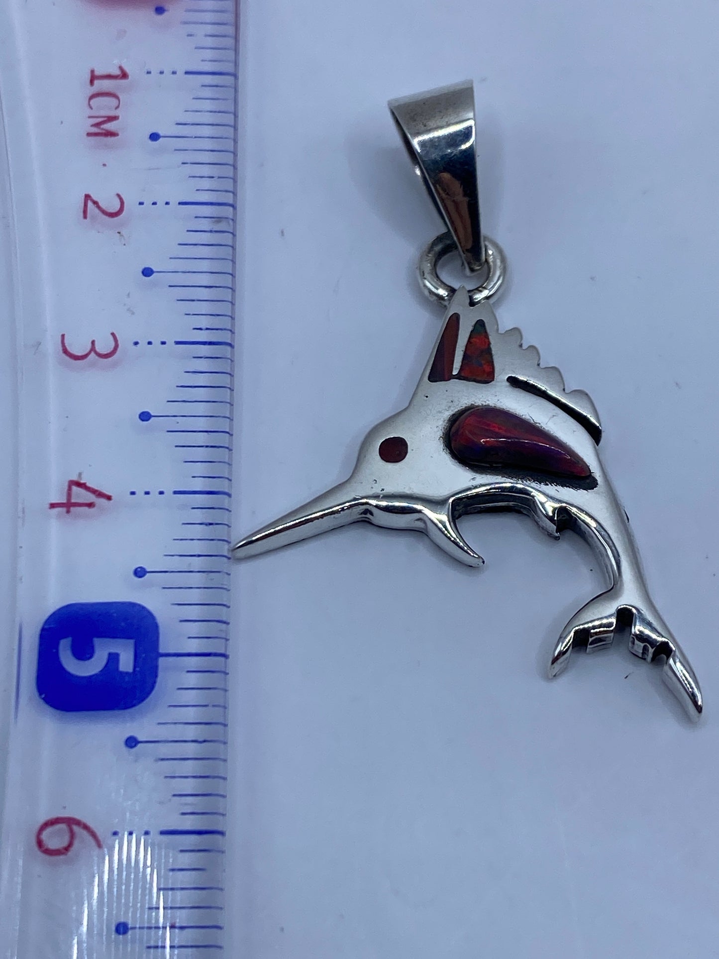 Detalle del ópalo de fuego multicolor incrustado en el lomo del tiburón de plata