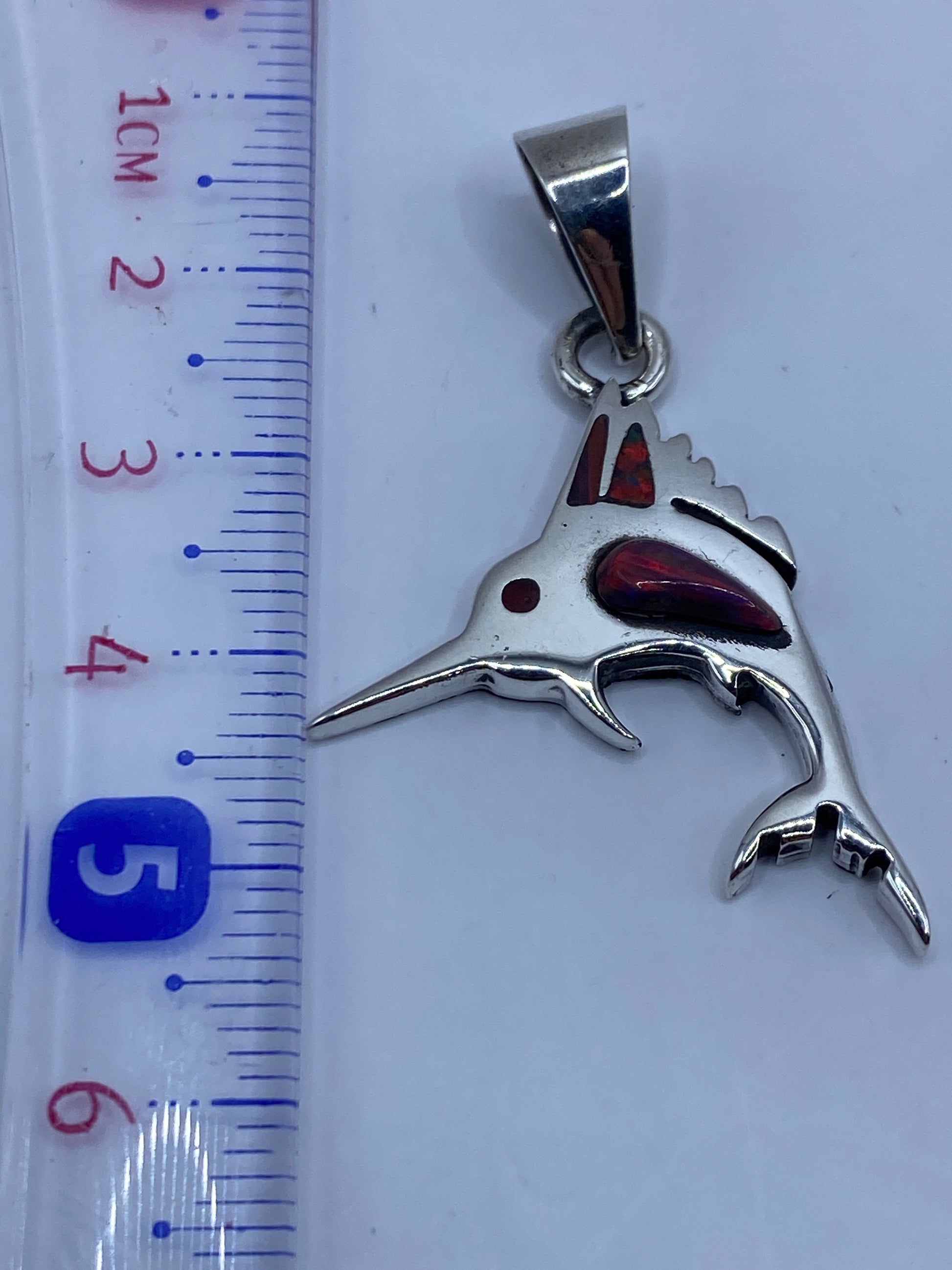 Detalle del ópalo de fuego multicolor incrustado en el lomo del tiburón de plata