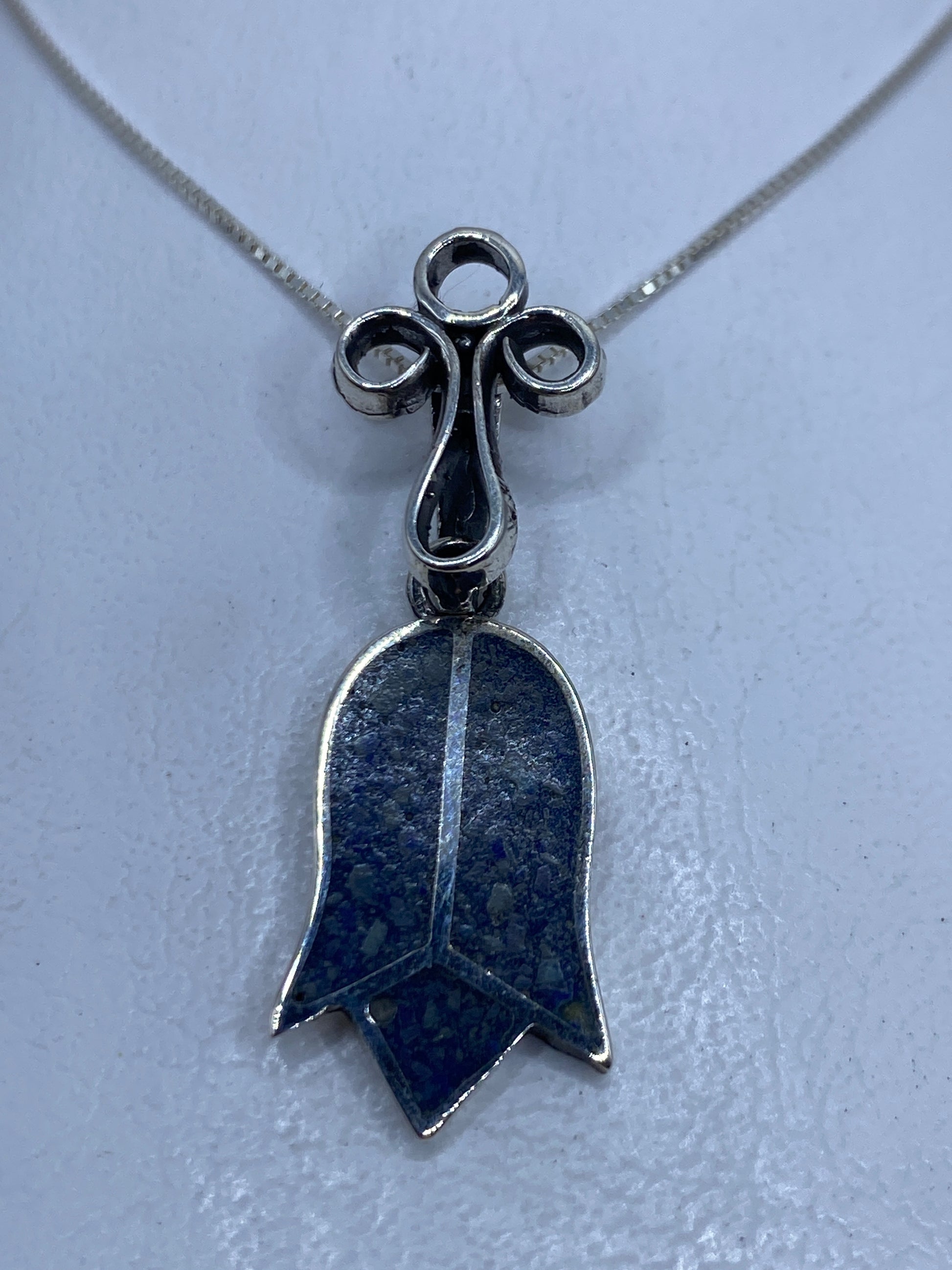 Dije campana de plata .925 con piedra azul incrustada, colgado de una cadena plateada fina