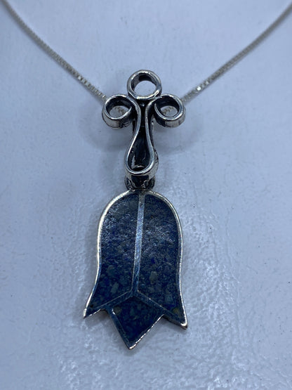 Dije campana de plata .925 con piedra azul incrustada, colgado de una cadena plateada fina