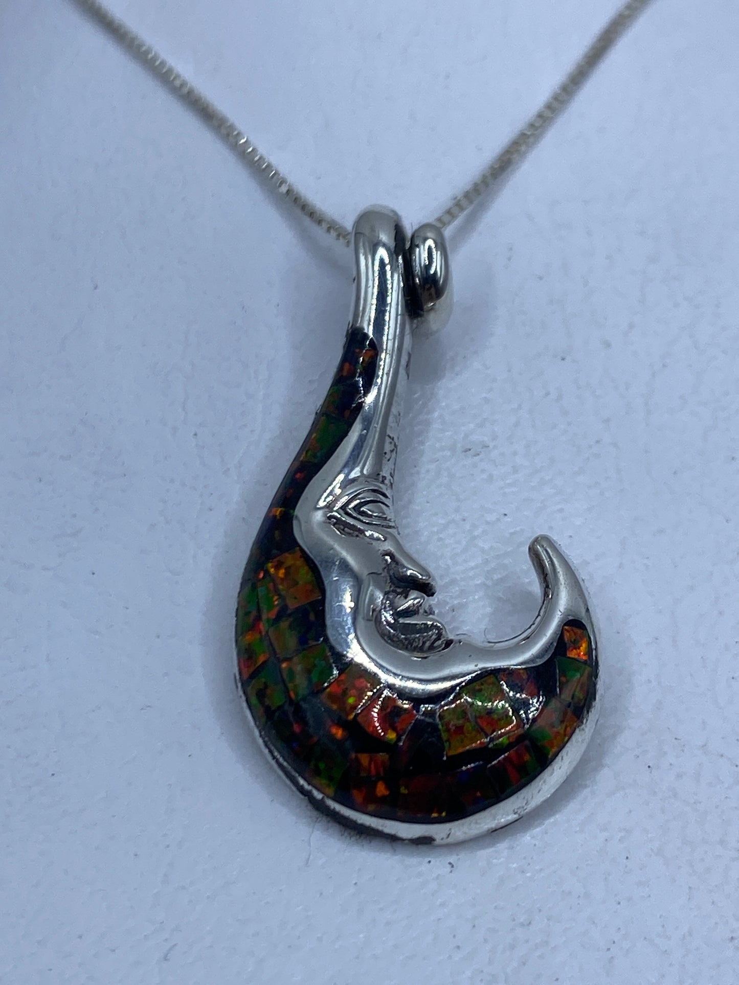 Dije de plata con ópalo de fuego multicolor que refleja naranja, rojo y verde al frente
