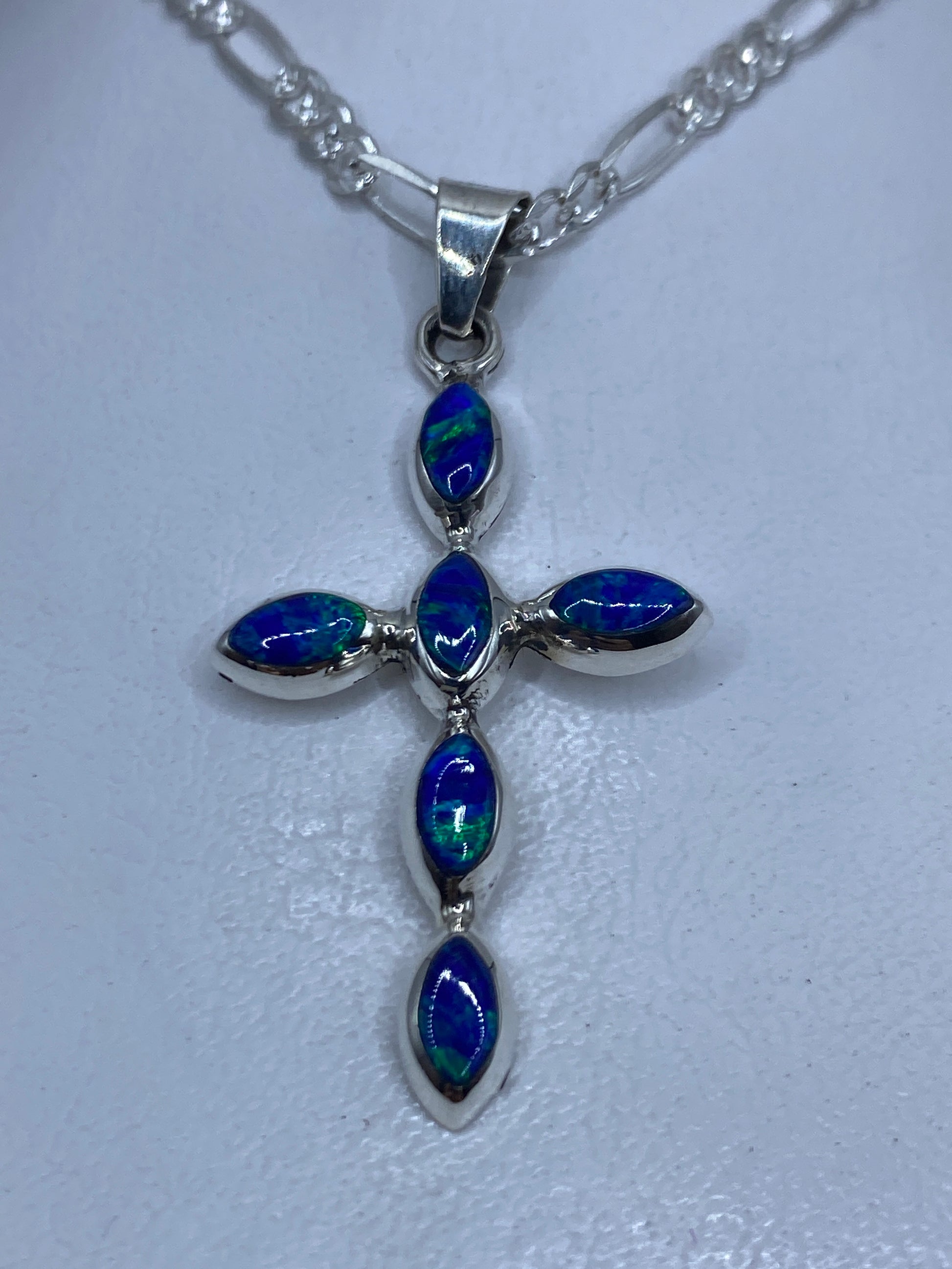 Dije cruz de plata con ópalo de fuego azul engastado, colgando de cadena
