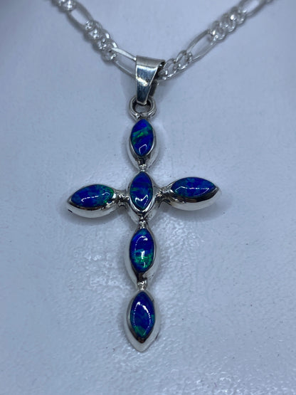 Dije cruz de plata con ópalo de fuego azul engastado, colgando de cadena
