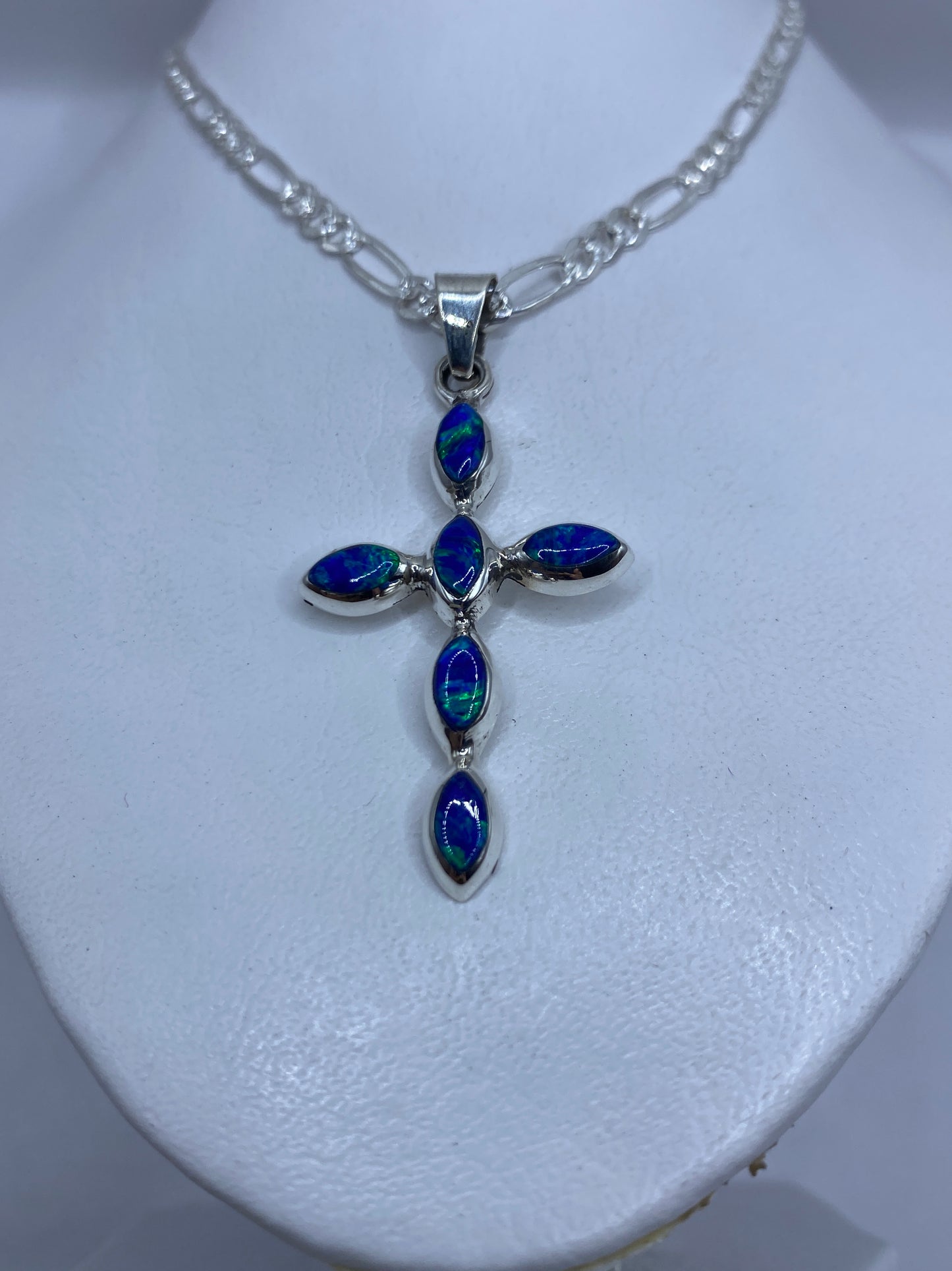 Detalle del engaste a mano del ópalo de fuego azul en la cruz de plata .950