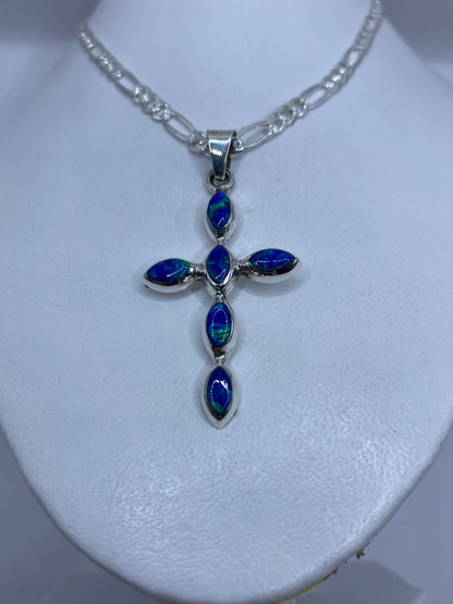 Detalle del engaste a mano del ópalo de fuego azul en la cruz de plata .950