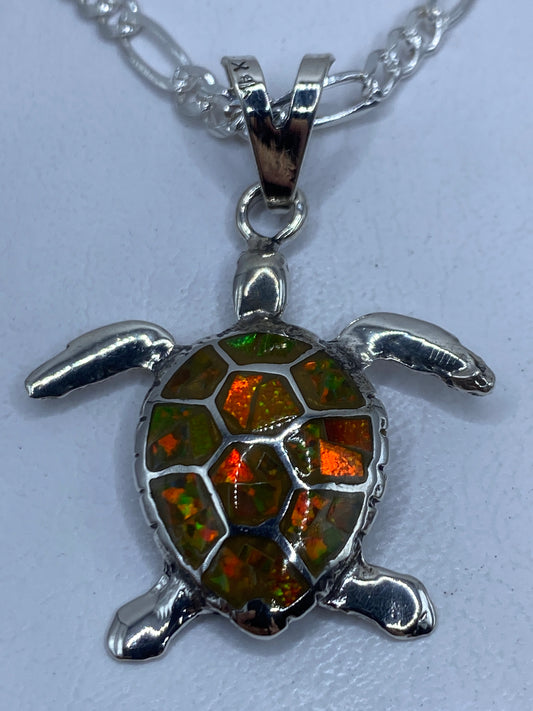 Dije tortuga de plata .950 con ópalo de fuego amarillo incrustado, colgando de una cadena Figaro pulida