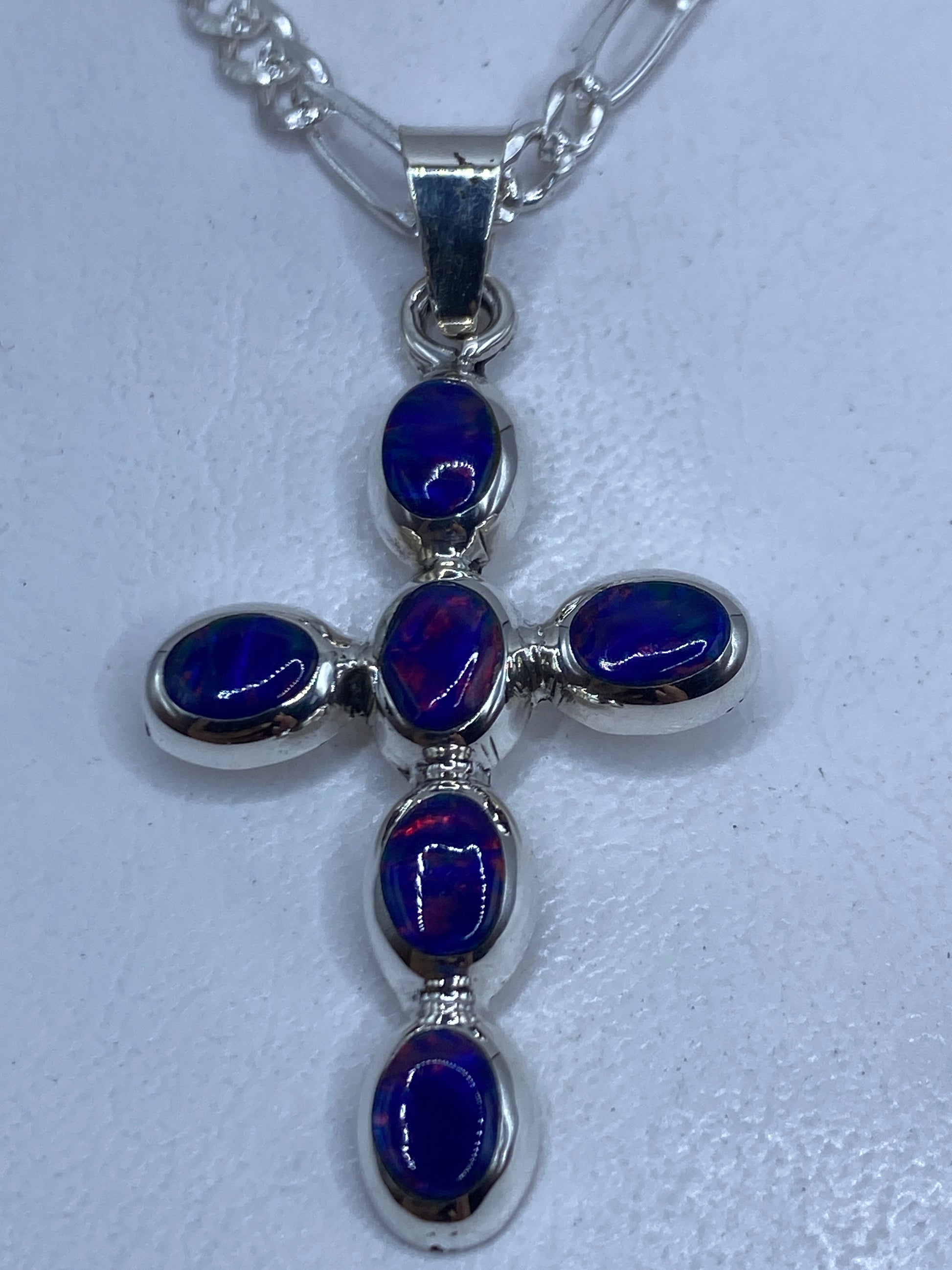 Cruz dije de plata .950 con ópalo de fuego azul, vista frontal sobre cadena