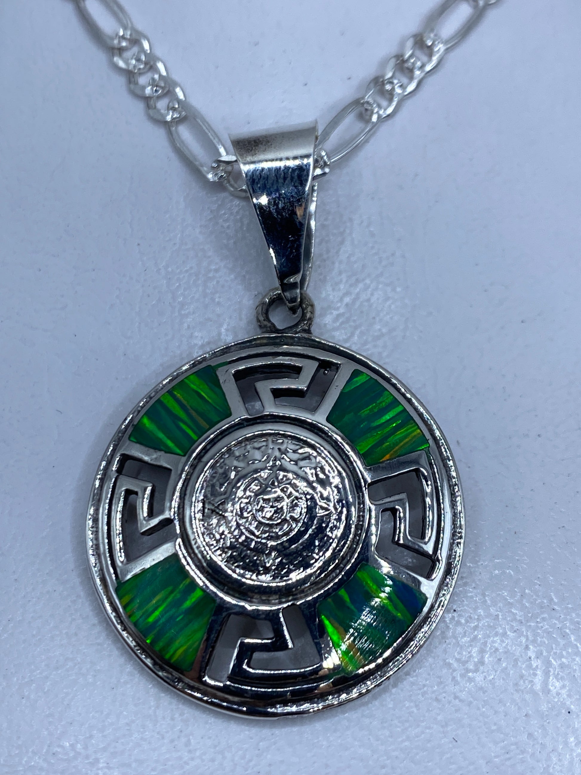 Dije circular de plata con ópalo de fuego verde incrustado, diseño prehispánico con grecas geométricas