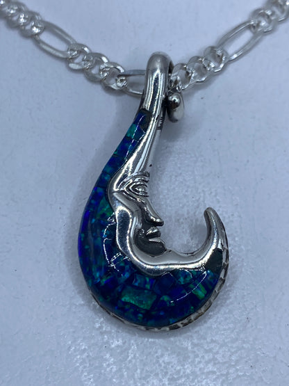 Dije de plata con forma de luna incrustada en ópalo de fuego azul, colgando de una cadena de plata