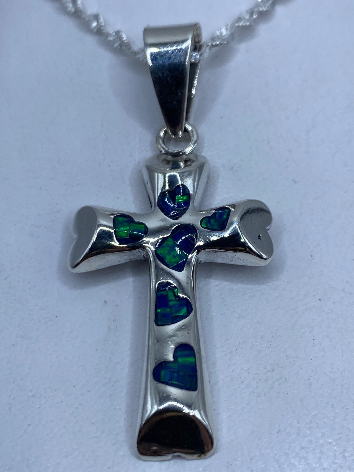 Dije cruz de plata .950 con ópalo de fuego azul engastado, sobre cadena de plata