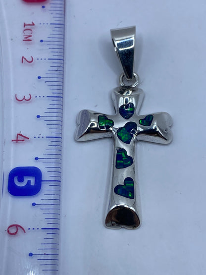 Dije cruz de 5.5 cm junto a regla de medición, mostrando escala real sin cadena